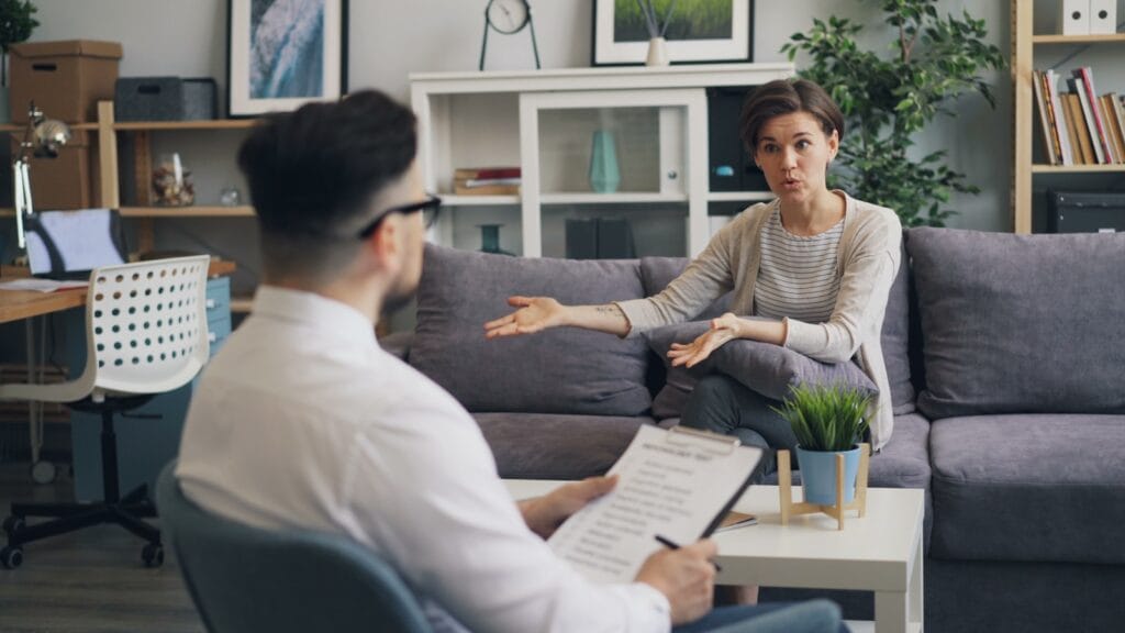a man sitting on a couch talking to a woman